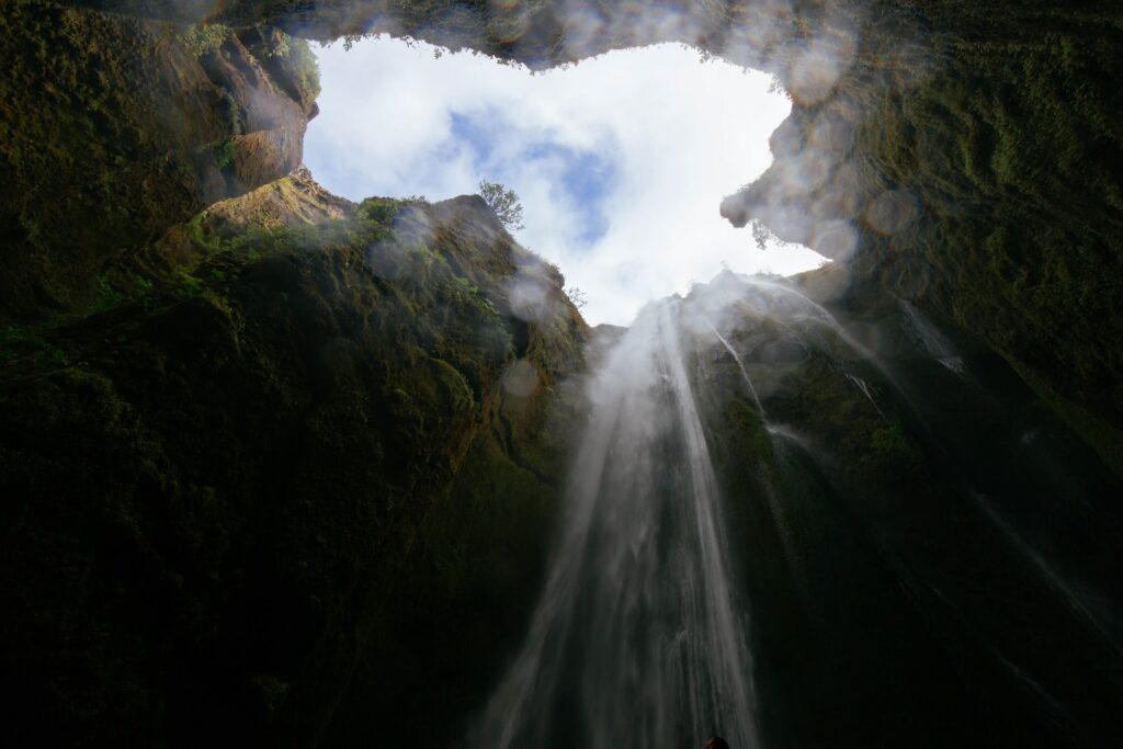 Wasserfall fällt von oben in eine Höhle